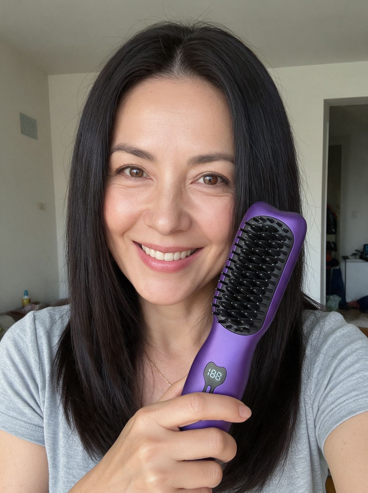 Femme souriante tenant la brosse lissante SORÉA Glide, cheveux lisses et brillants